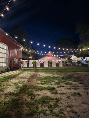 Night scene with string lights and tents decorated for a celebration.