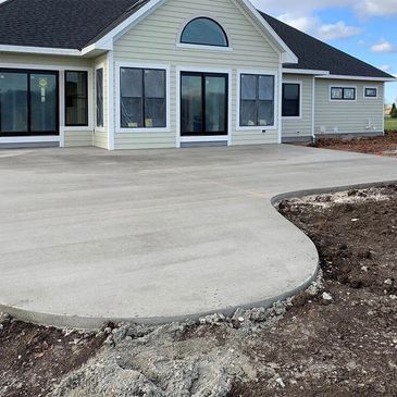 Newly poured concrete patio outside a modern house.