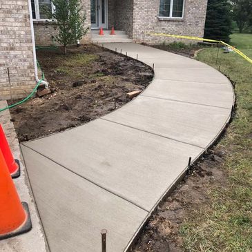 A freshly poured concrete sidewalk leading to a house entrance.