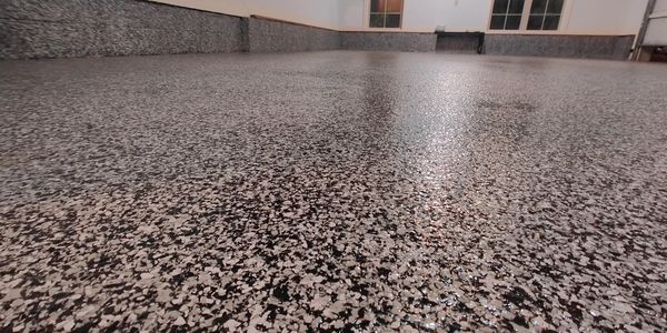 A newly finished epoxy-coated garage floor with black and white flakes.
