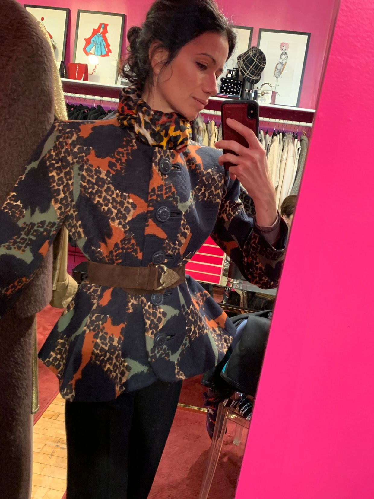 Woman takes a mirror selfie wearing a patterned jacket with a belt.