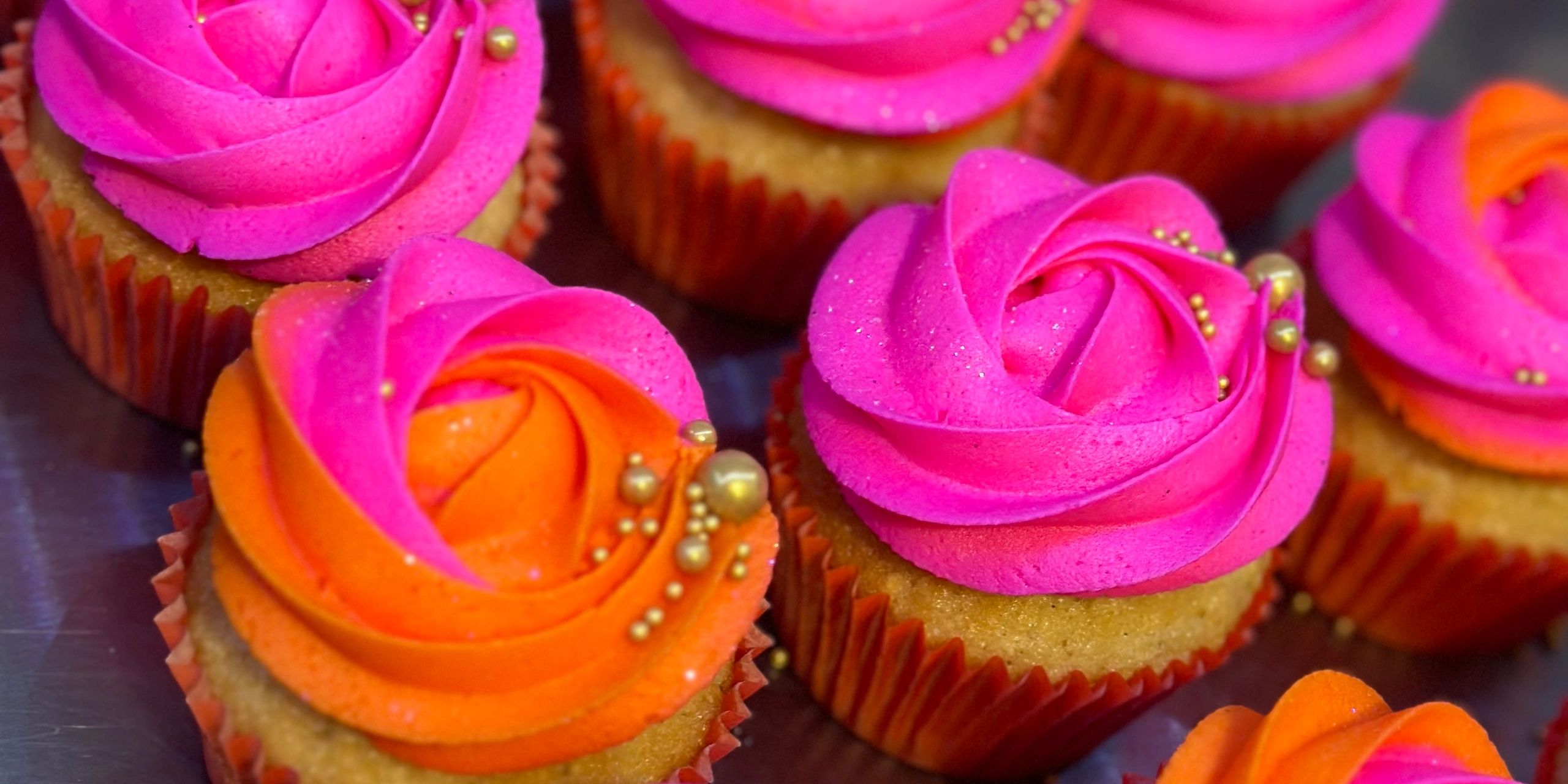 Colorful cupcakes with vibrant pink and orange frosting.
