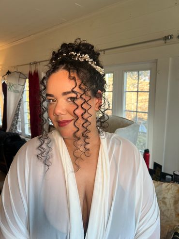 Woman with curly hair and pearl hair accessory.