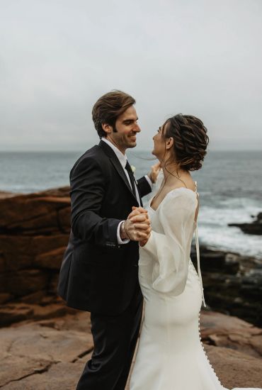 Couple dancing on rocky shore.