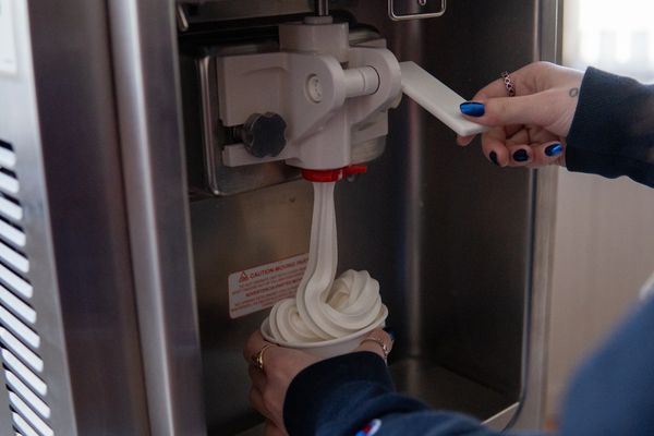 Soft serve ice cream being dispensed into a cup from a machine.