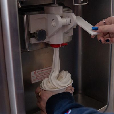 Soft serve ice cream being dispensed into a cup from a machine.
