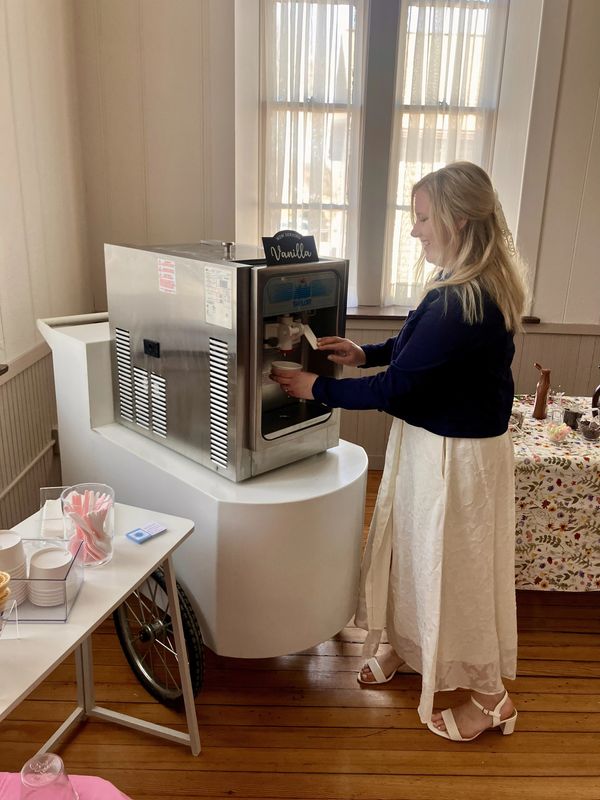 Woman serving herself vanilla soft-serve ice cream indoors.