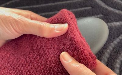 Hands polishing a black stone with a red cloth.