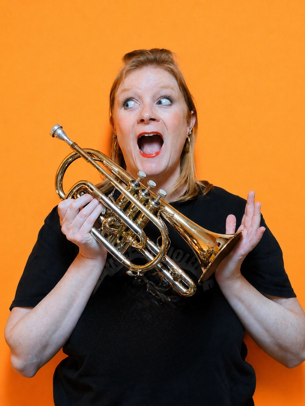 Woman holding a trumpet with an expressive open mouth against an orange background.