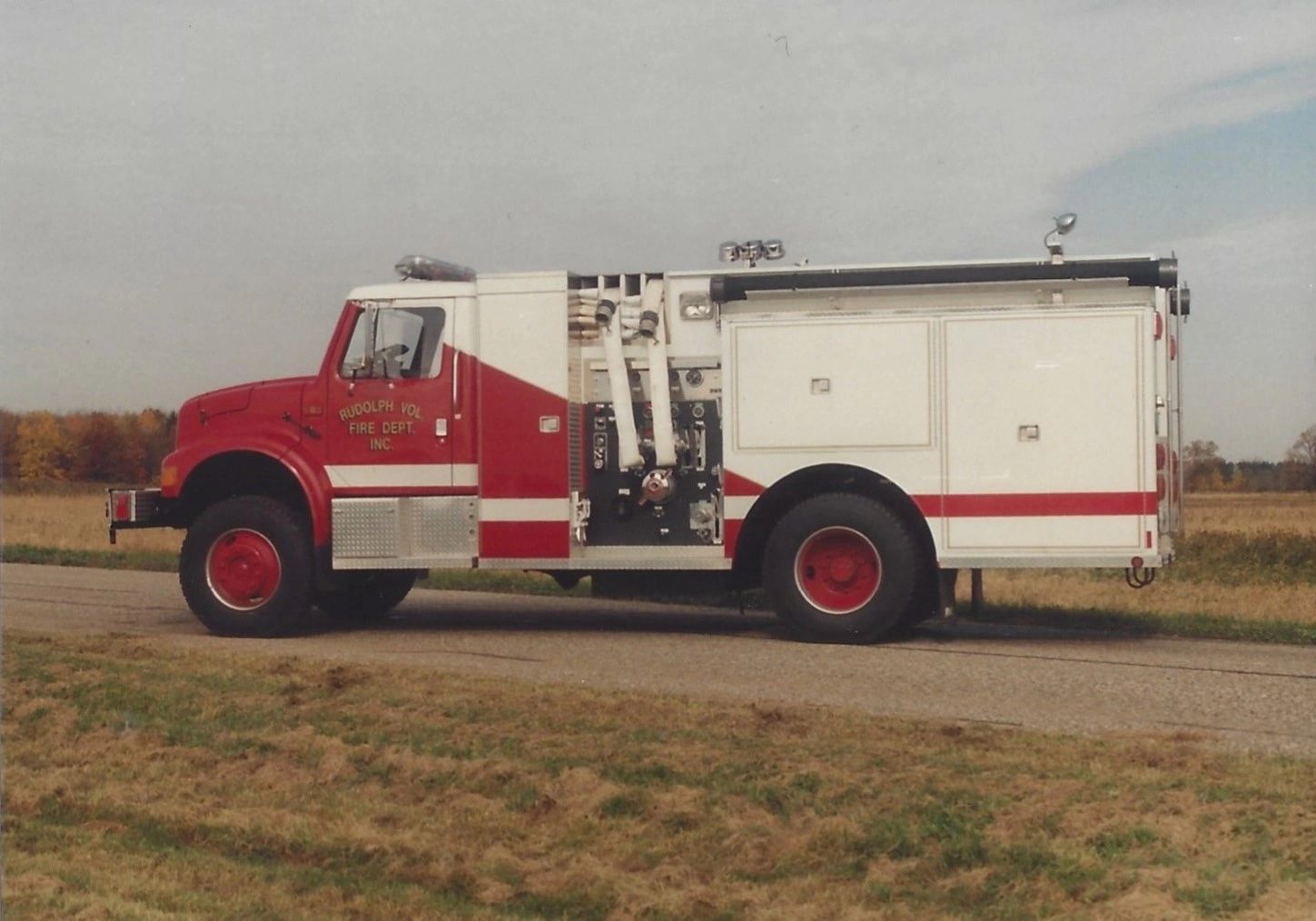 Side view of a red and white fire truck parked on a road.