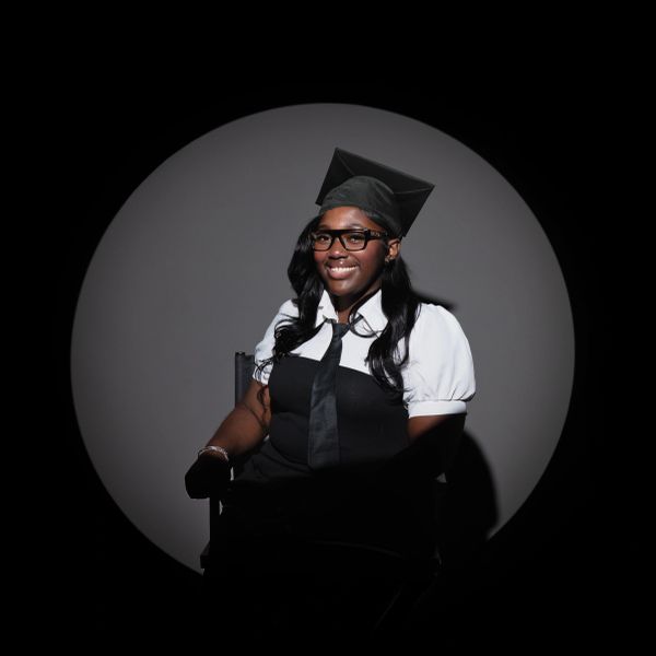 Woman in graduation cap and gown smiling.