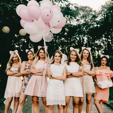 Seven women dressed pink, holding some balloons that just came back from bachelorette party
