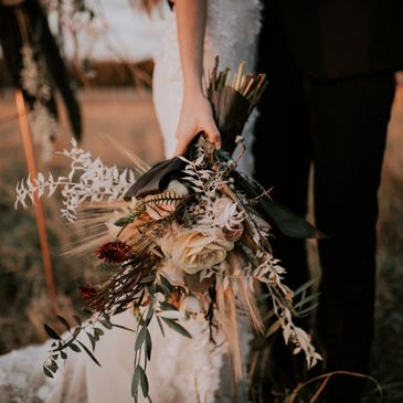 A just wed couple in boho style holding a bunch of flowers