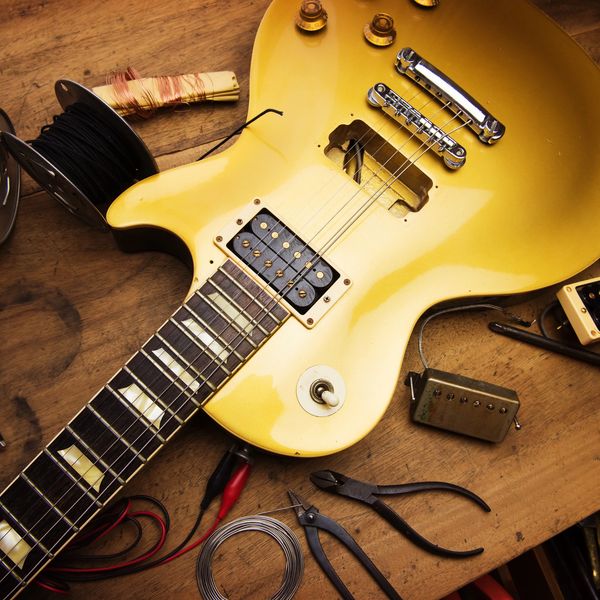 "Guitar repair bench with tools and a disassembled guitar."