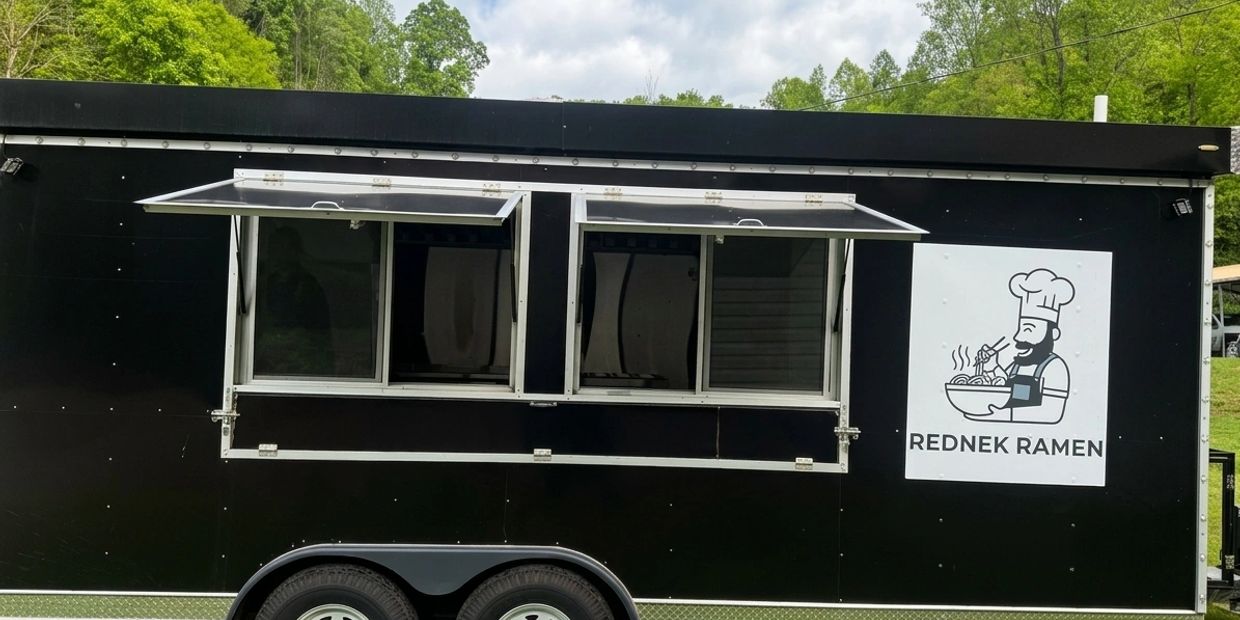 Black food truck with open serving windows and Rednek Ramen logo.
