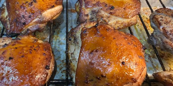 Grilled chicken thighs with crispy, golden-brown skin on a rack.