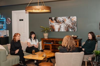 Four women sitting and chatting in a cozy living room with modern decor.