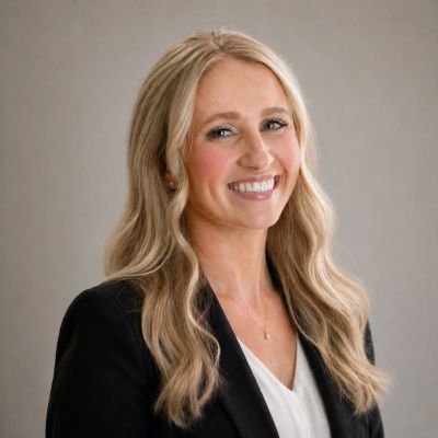 Professional woman with long blonde hair smiling in a business portrait.