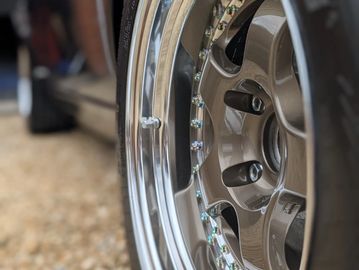 Close-up of a polished car wheel rim with bolts.