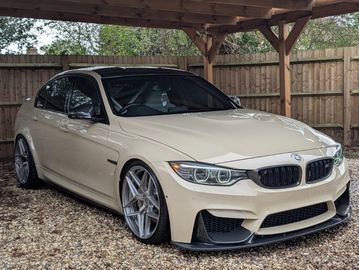 White BMW sedan parked under wooden shelter.