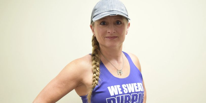 Woman in a blue tank top and cap smiling at the camera.