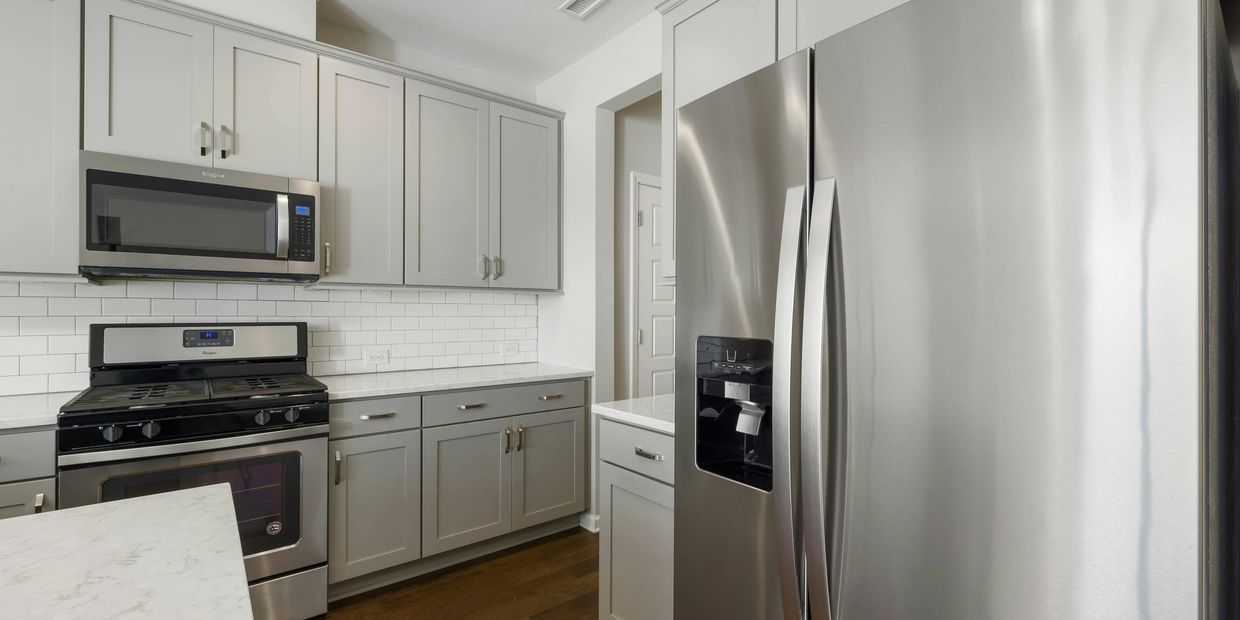 Modern kitchen with stainless steel appliances and gray cabinetry.