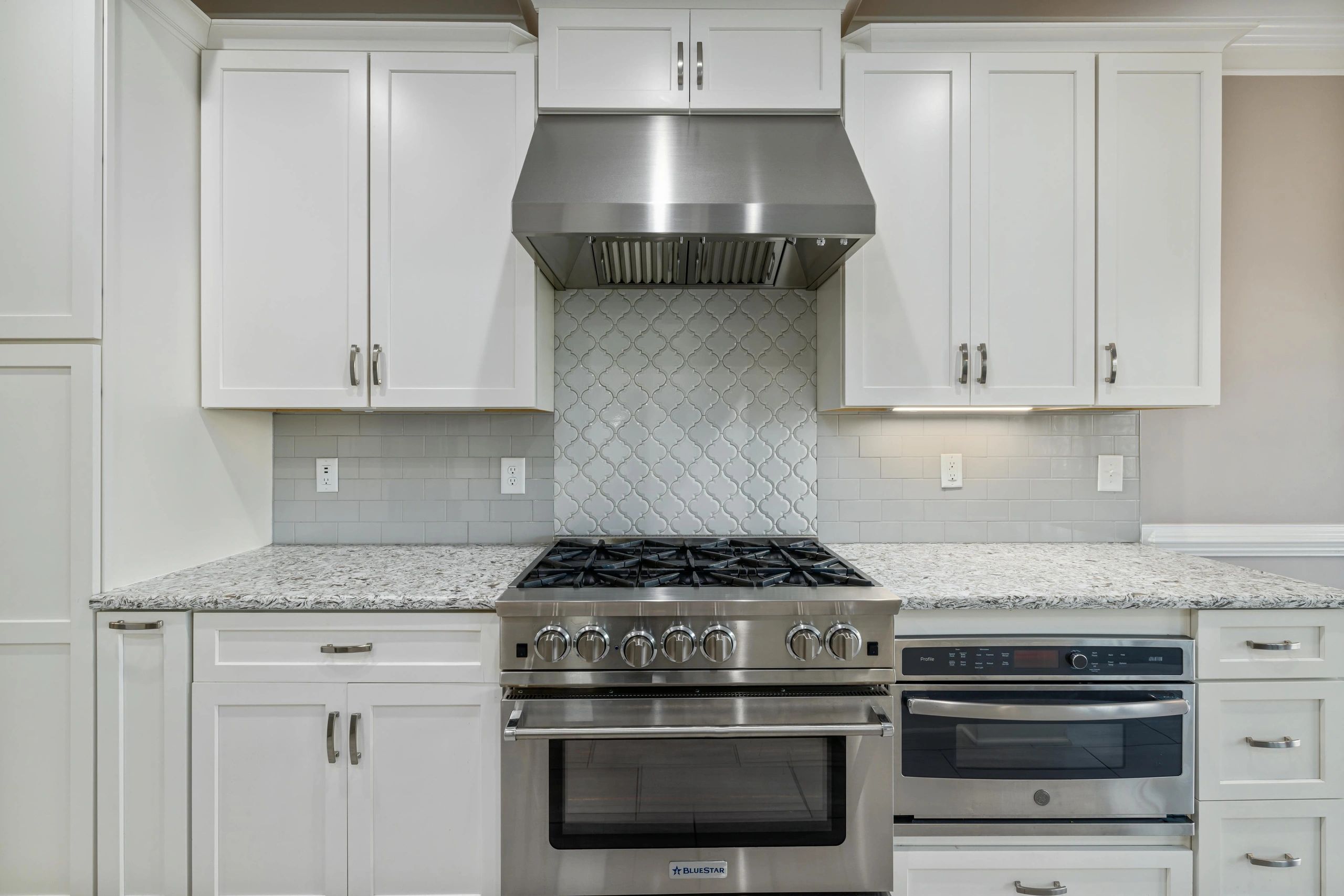 Modern kitchen with stainless steel stove and white cabinets.
