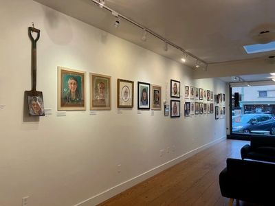 Art gallery wall with various portraits and a shovel display.