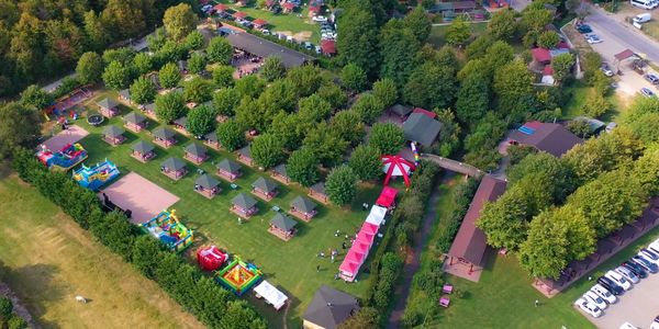 Aerial view of a colorful outdoor park with tents and inflatables.