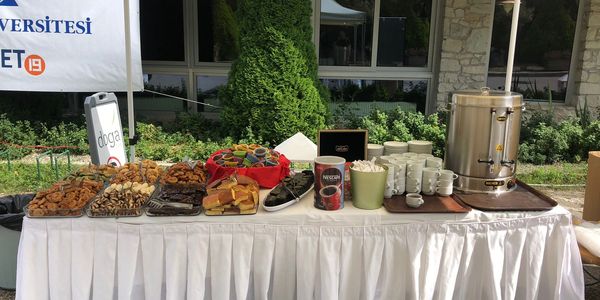 Outdoor buffet table with snacks, desserts, and a large beverage dispenser.