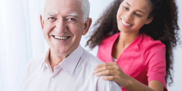 an elderly man standing in front of a nurse in pink scrubs