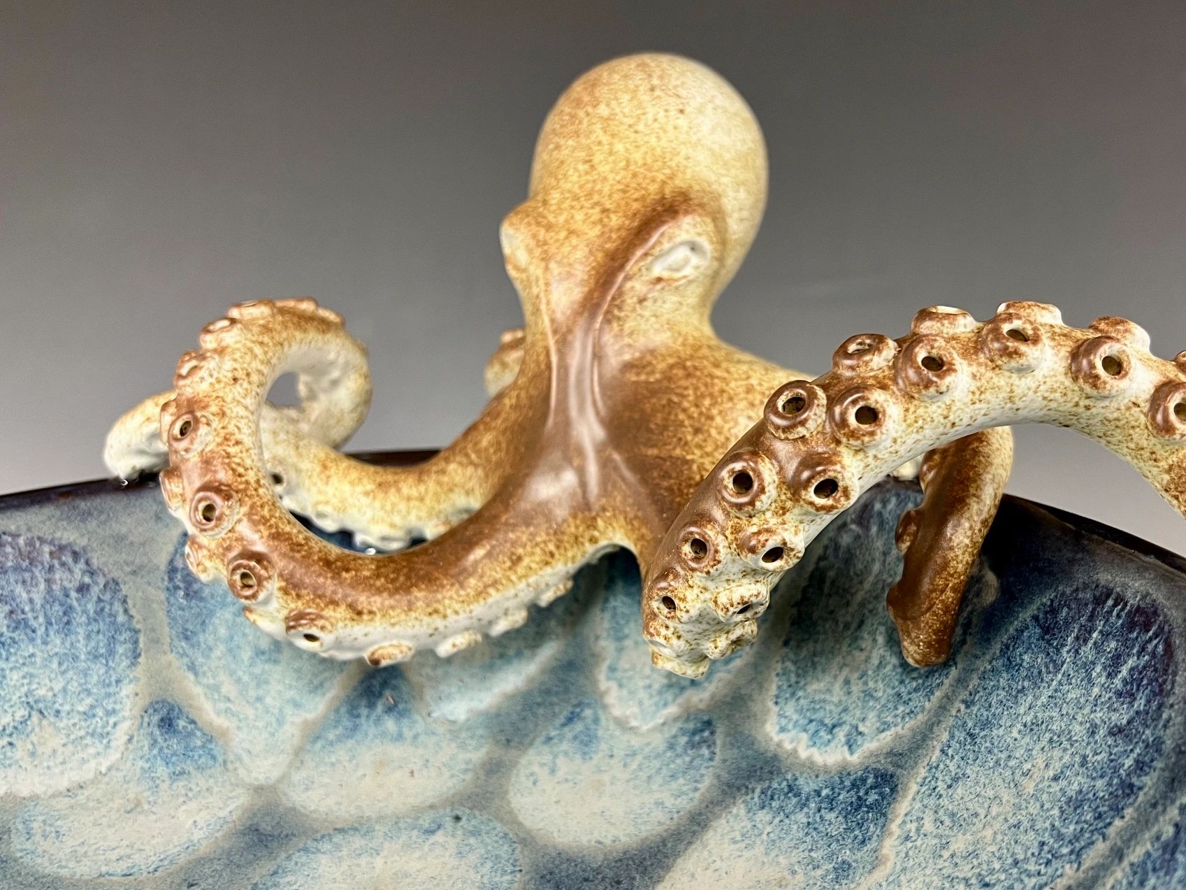 Realistic ceramic octopus figurine inside a blue bowl.