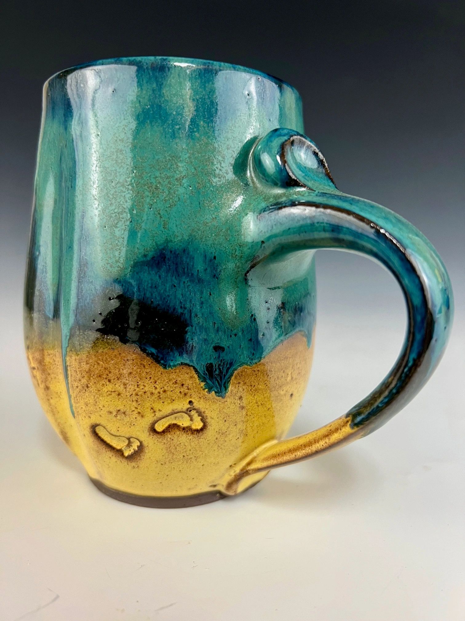 Close-up of a ceramic mug with teal and yellow glaze.
