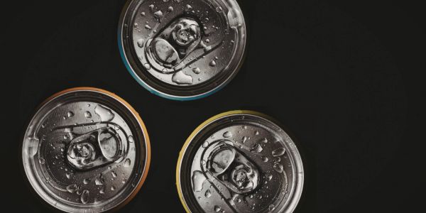 Three cold soda cans with water droplets on black background.