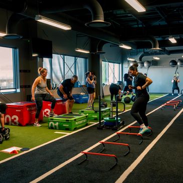 Group fitness class doing various exercises in a gym.