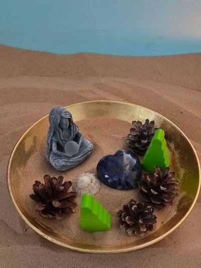 Objects in sand in a small gold bowl within a larger blue sand tray. 