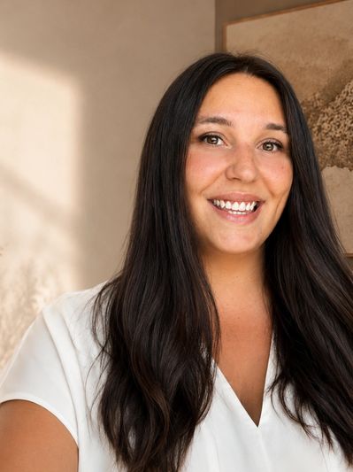 Smiling woman with long dark hair in a white blouse.