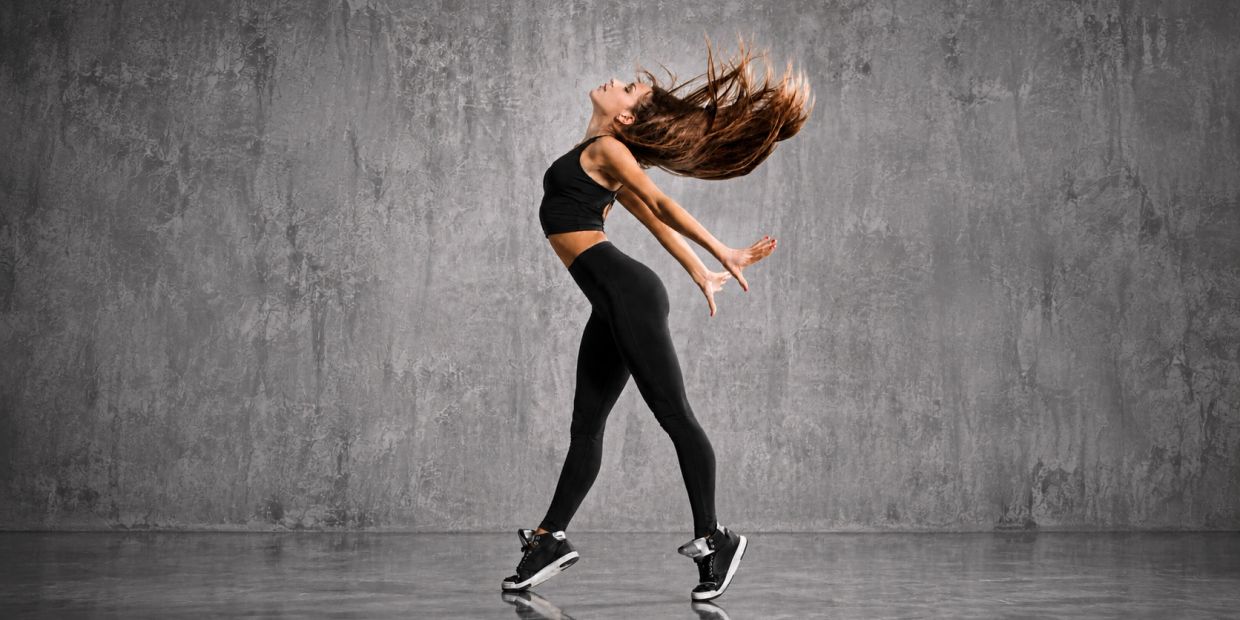 Woman in black sportswear striking a dynamic dance pose.