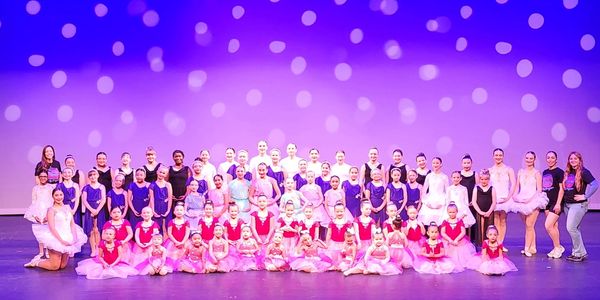 Large group of young ballet dancers posing on stage.