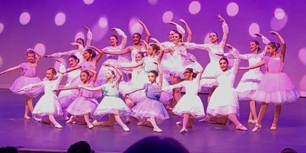 Group of young ballerinas performing on stage.