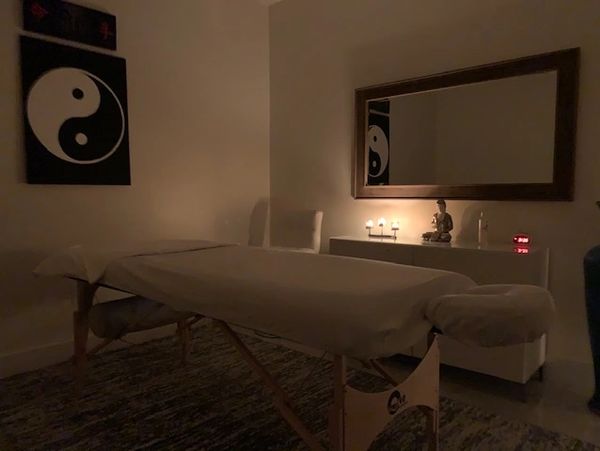 Dimly lit massage room with a treatment table and calming decor.