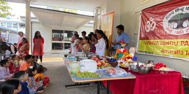Community event with people gathered around tables of food and offerings.