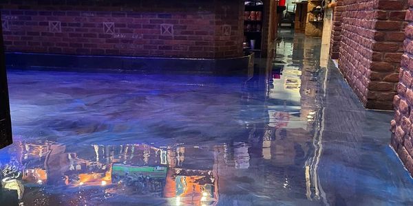 Reflective epoxy floor with brick walls and warm lighting.