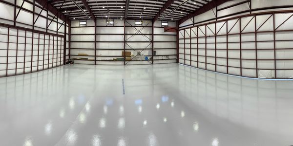 Empty spacious industrial warehouse with polished concrete floor and metal framework.