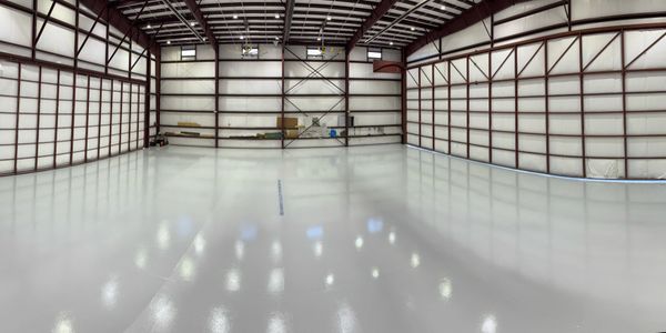 Empty spacious industrial warehouse with polished concrete floor and metal framework.