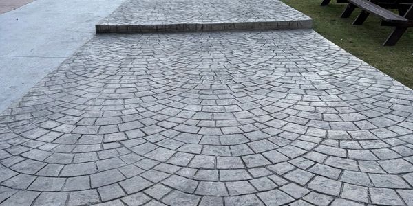 Patterned stone pavement with a raised platform and benches nearby.