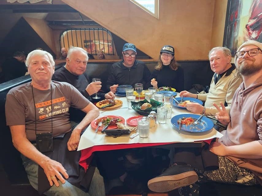 Group of six people enjoying a meal together at a restaurant.