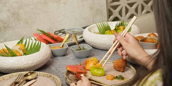 Person using chopsticks to eat colorful gourmet food.