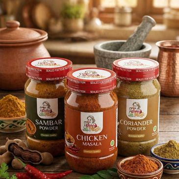 Three jars of Indian spice powders on a kitchen counter with ingredients.