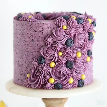 Purple frosted cake decorated with blueberries and yellow candies.